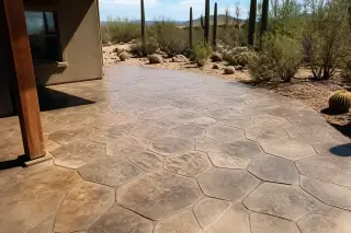 Stamped concrete patio with stone masonry patterns and saguaro cacti in a Tucson, AZ desert landscape.
