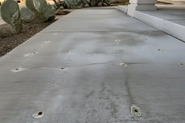 Sunken concrete leveling with drill ports and polyurethane foam on a Tucson, AZ jobsite with nearby prickly pear cacti.