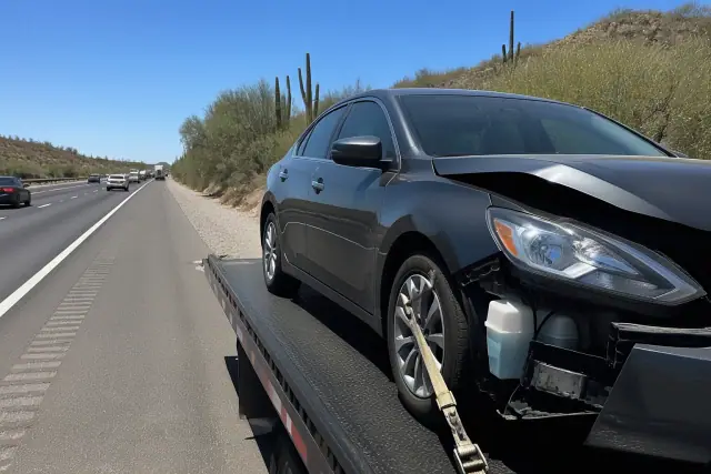 Disabled sedan secured on a flatbed truck on a busy highway in Catalina Foothills, AZ.