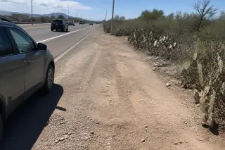 Cleared highway shoulder with tire marks and prickly pear cacti in Tucson, AZ.