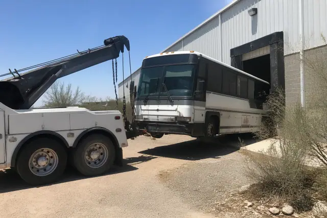 Heavy-duty wrecker truck recovering a bus at an industrial loading bay in Tucson, AZ.