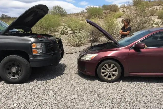 Jump-start service vehicle parked nose-to-nose with a sedan on a gravel lot in Catalina Foothills, AZ.