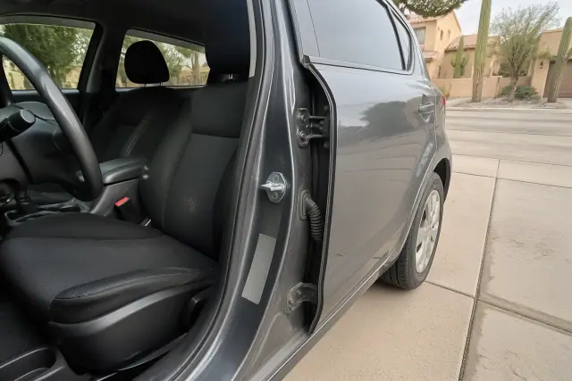 Lockout tool opening a car door to reveal the door-jamb GVWR label location in a Tucson, AZ driveway.