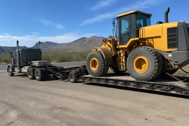 Heavy-duty tow truck and transport trailer parked in the Tucson, AZ desert with mountain views.