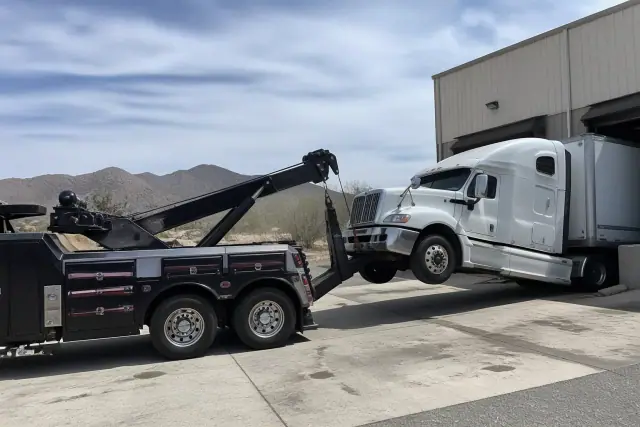 Heavy-duty wrecker truck lifting a commercial semi-truck at an industrial loading dock in Green Valley, AZ.