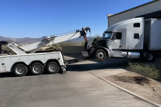 Heavy-duty wrecker truck lifting a semi-truck at a loading dock in the desert landscape of Vail, AZ.
