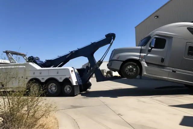 Heavy-duty wrecker truck lifting the front axle of a semi-truck at an industrial loading dock in Oro Valley, AZ.