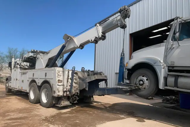 Heavy-duty wrecker truck lifting a commercial semi-truck axle at an industrial site in Tucson, AZ.