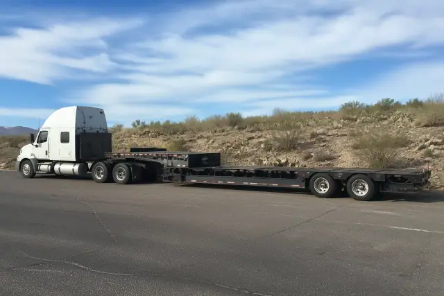 Medium-duty tow truck with a long-distance transport trailer parked in the desert landscape of Tucson, AZ.