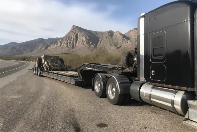 A heavy-duty tow truck pulling a transport trailer on a roadside near mountains in Tucson, AZ.