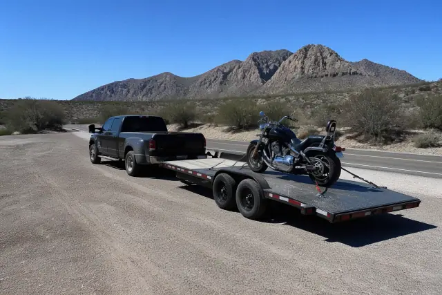 A transport trailer with a strapped motorcycle hooked to a truck in the desert near Tucson, AZ.
