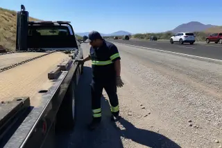 Technician performing a final safety inspection of a vehicle on a gravel highway shoulder in Tucson, AZ.