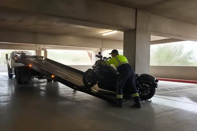 A tow truck securing a motorcycle on a ramp inside a concrete parking structure in Marana, AZ.