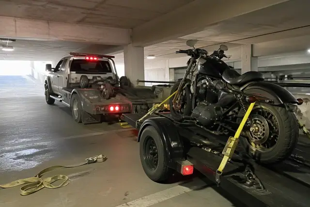 Motorcycle secured with ratchet straps on a trailer in a concrete parking garage in Tucson, AZ.
