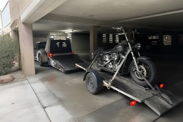 A motorcycle secured on a tilt-bed trailer being towed inside a concrete parking structure in Vail, AZ.