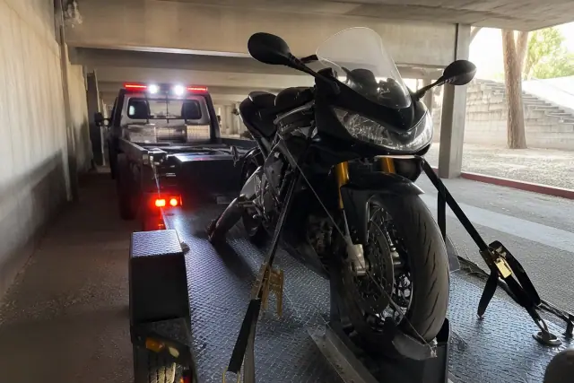 Motorcycle secured with specialized tie-downs on a trailer inside a parking structure in Tucson, AZ.