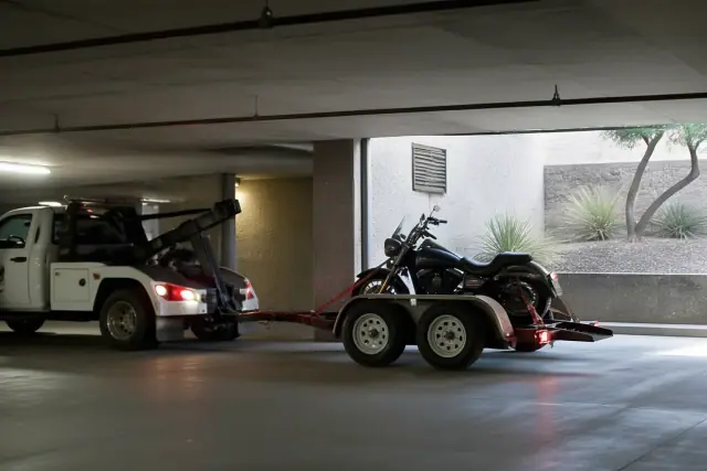 Low-clearance tow truck maneuvering to pick up a motorcycle in a Tucson, AZ underground parking garage.