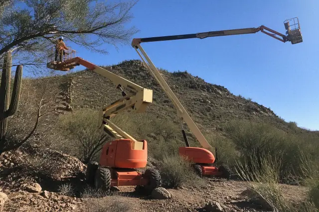 Two boom lifts parked on rocky terrain in Tucson, AZ for a site access and reach comparison.