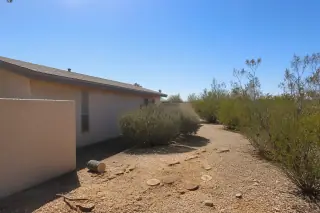 Cleared tree canopy space above a stucco house roof with gravel landscaping and wood chips in Tucson, AZ.