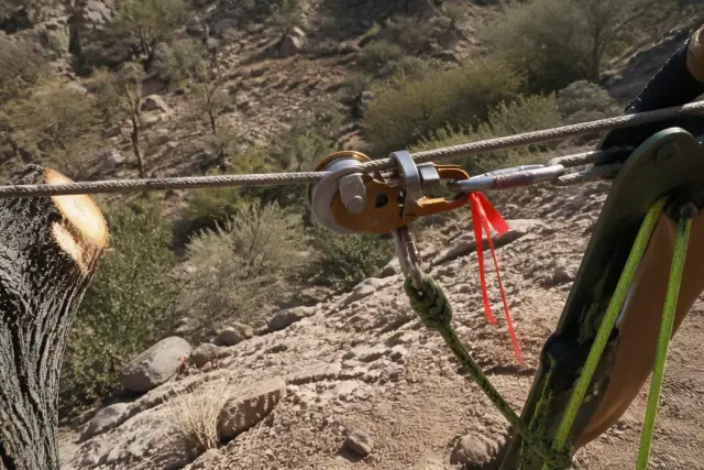 Security tag attached to a rigging rope during a lowering operation in Tucson, AZ with desert vegetation in the background.