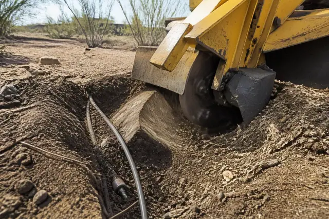 Stump grinder pulverizing a tree stump into mulch near irrigation lines in Tucson, AZ.